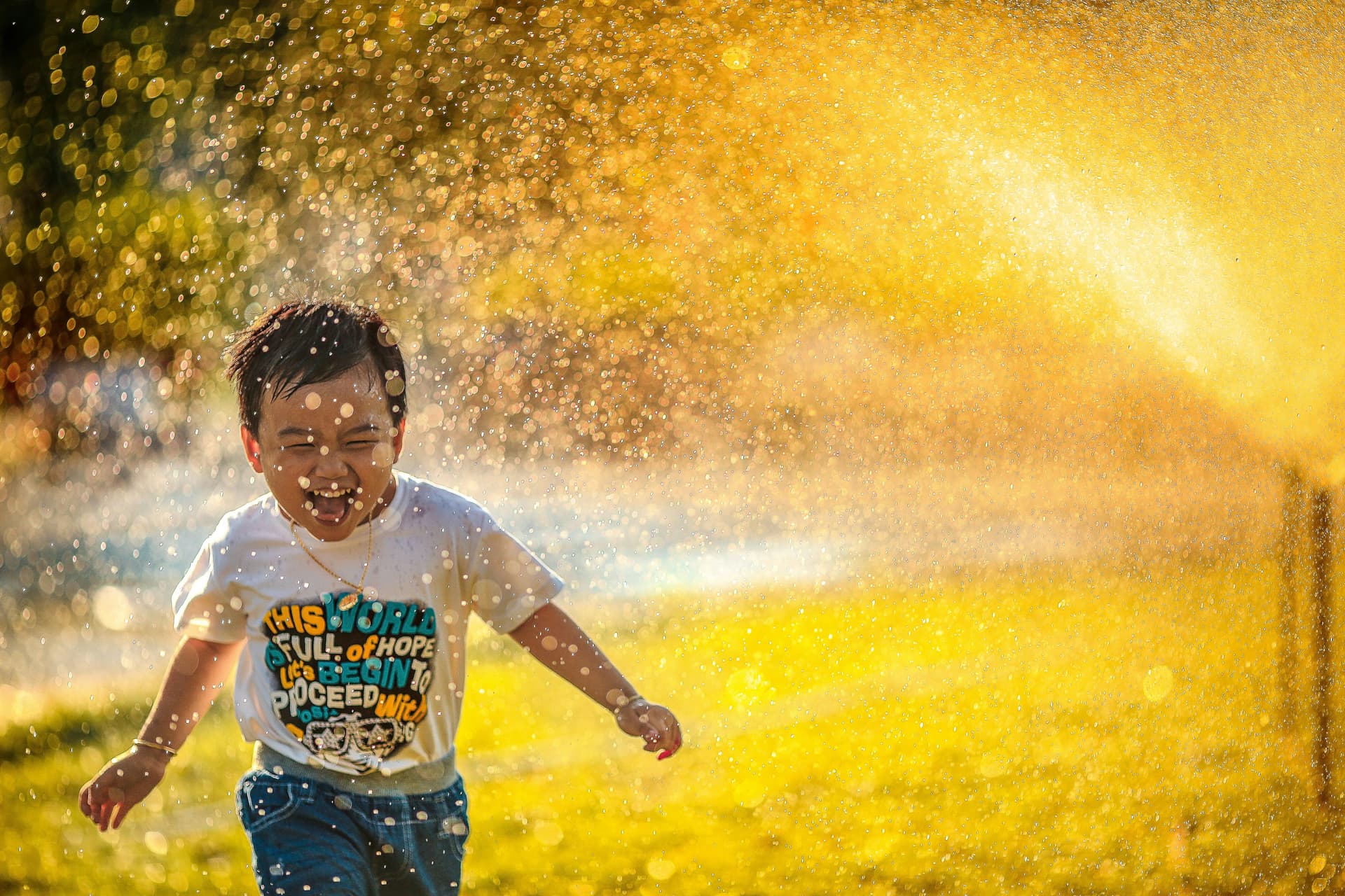Kid running through sprinkler